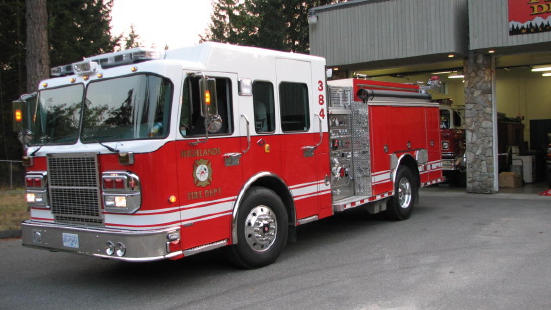 Red fire truck parked outside of fire station.